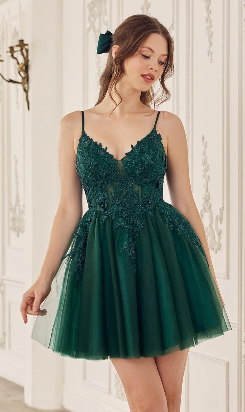 A woman stands indoors against a decorative white wall wearing the Short Babydoll Homecoming Dress: CLSF047, featuring a sleeveless embroidered lace bodice and a flared tulle skirt.